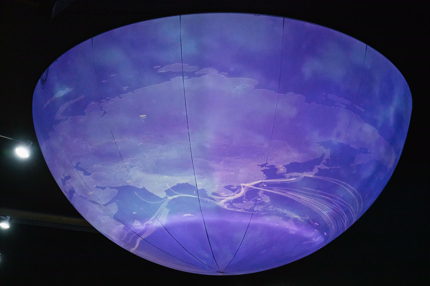 The sphere carrying a violet sky, cloud and a suggestion of coastline wrapping around its lower half.