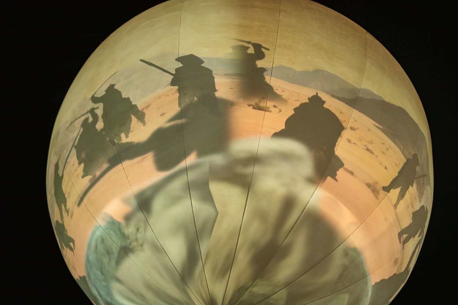 A sepia photograph wrapped around the sphere, figures silhouetted as if walking over the curve.