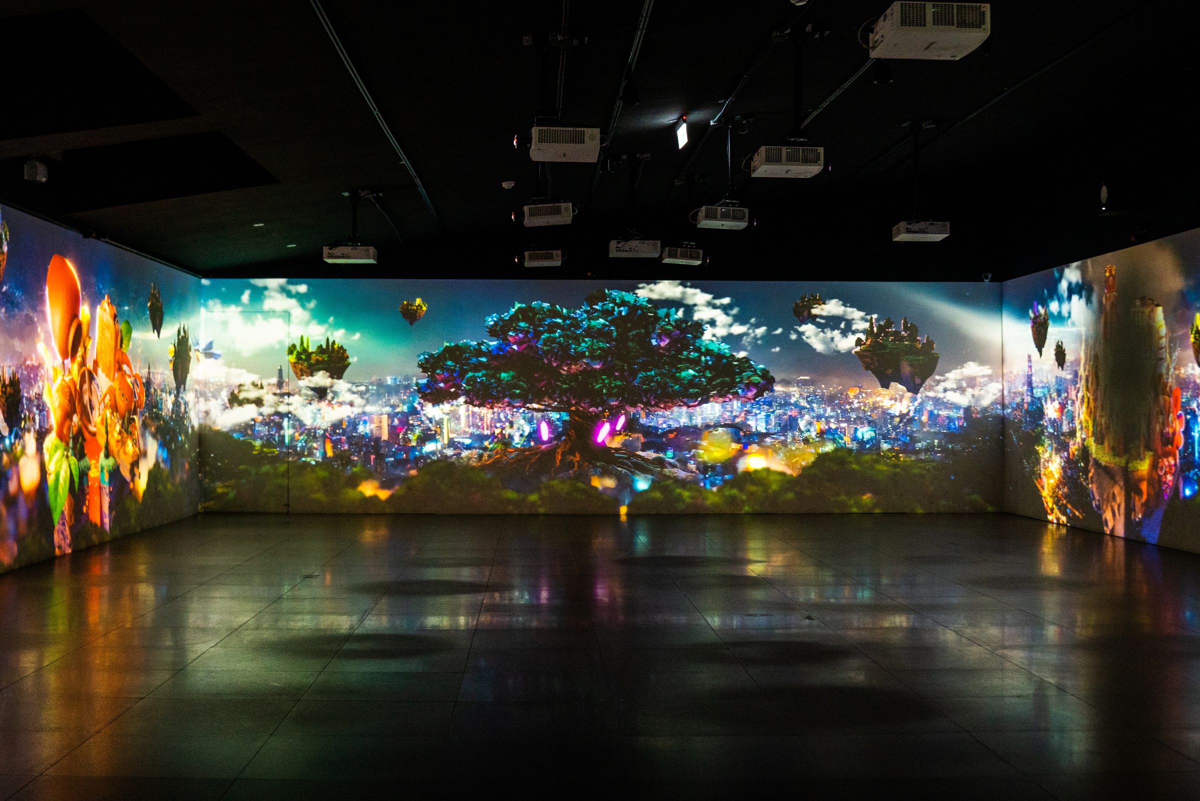Children's hand-drawn creatures projected across three walls of a darkened gallery at the New Taipei City Art Museum.