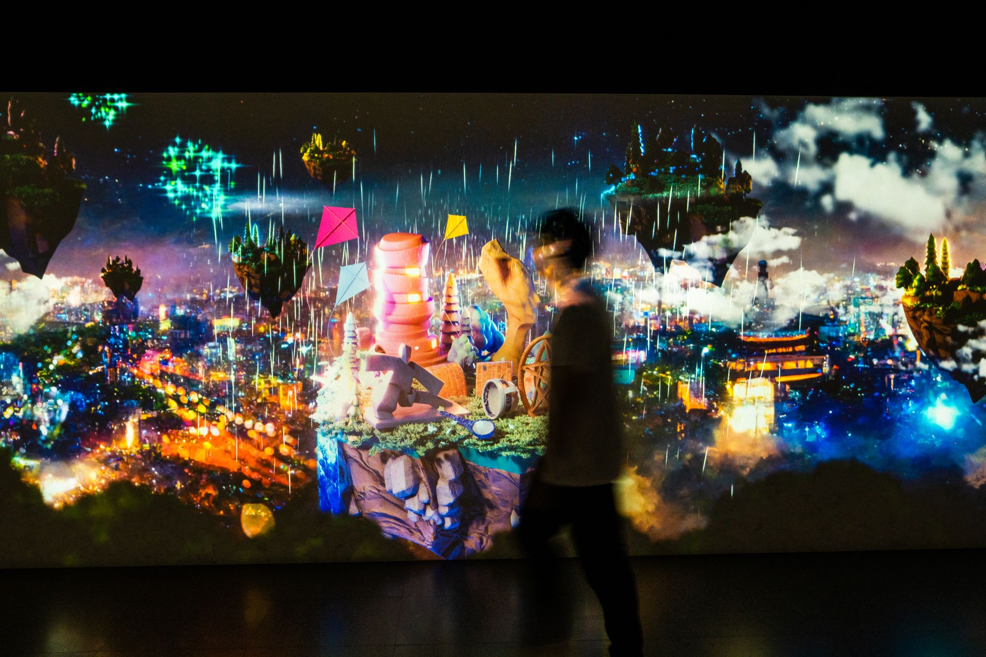A child kneels close to the projection, tracking their creature with a raised hand.